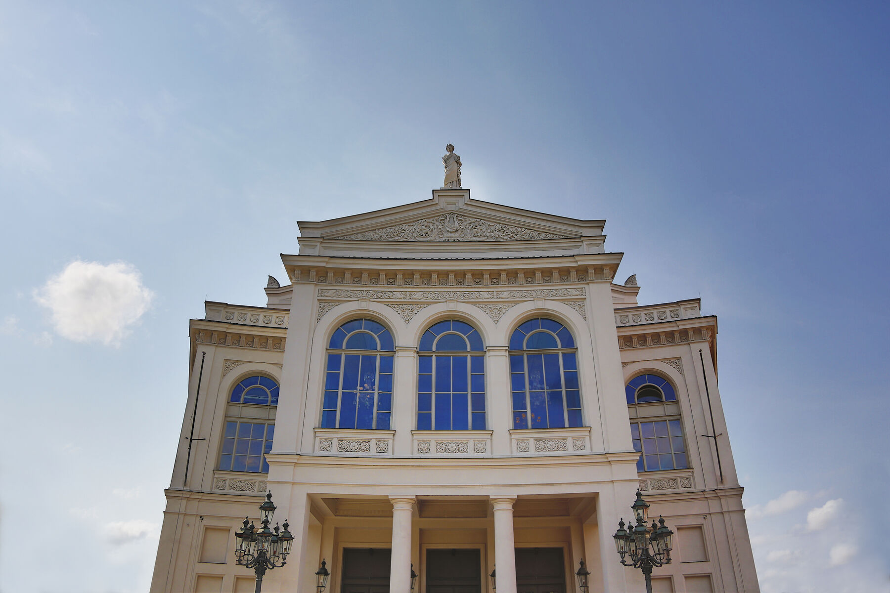 Blick von unten auf das Theatergebäude am Gärtnerplatz mit blauem Himmel.