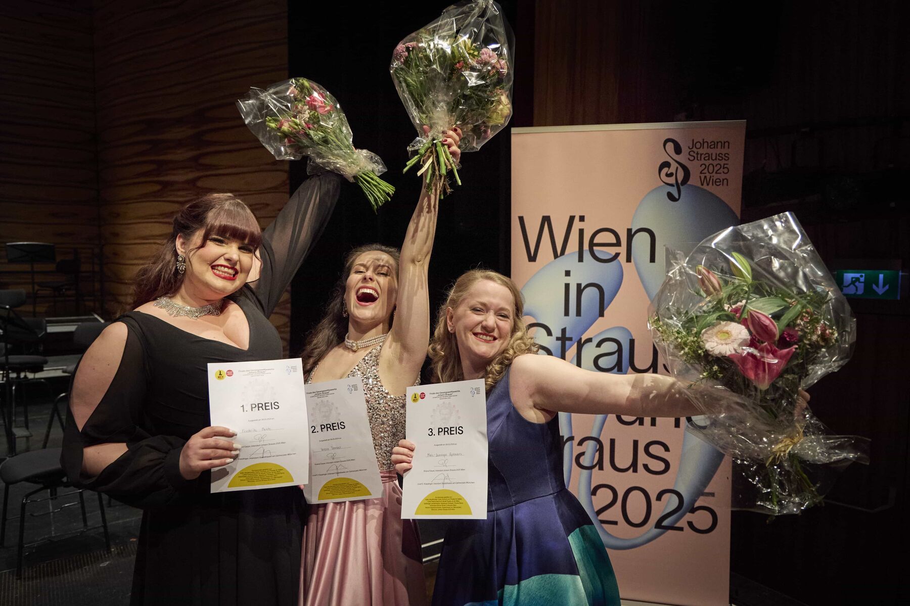 The top three contestants in the 2024 competition celebrate their success and hold their bouquets of flowers in the air.
