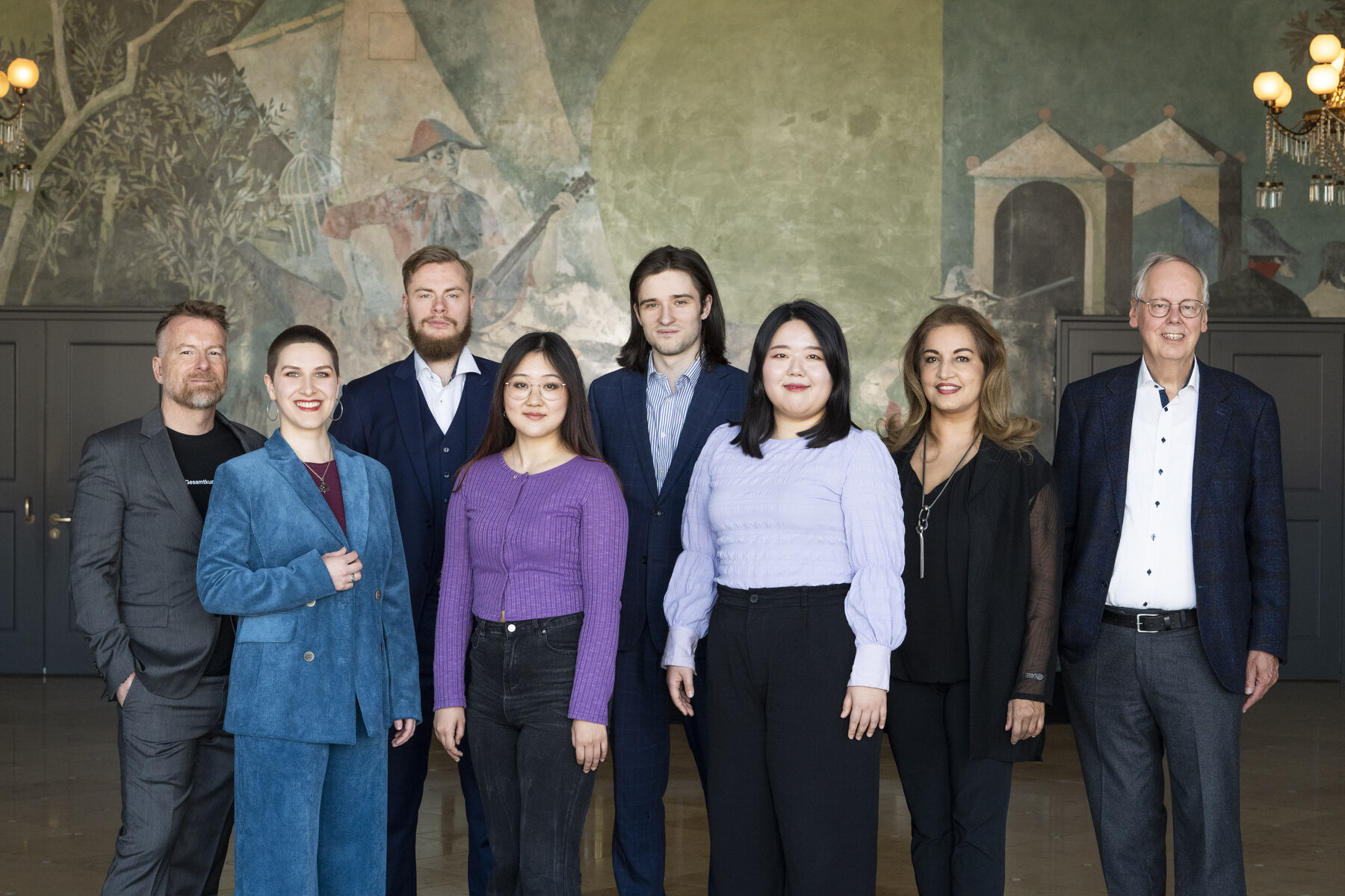 The six members of the opera studio and the team are lined up and looking at the camera.