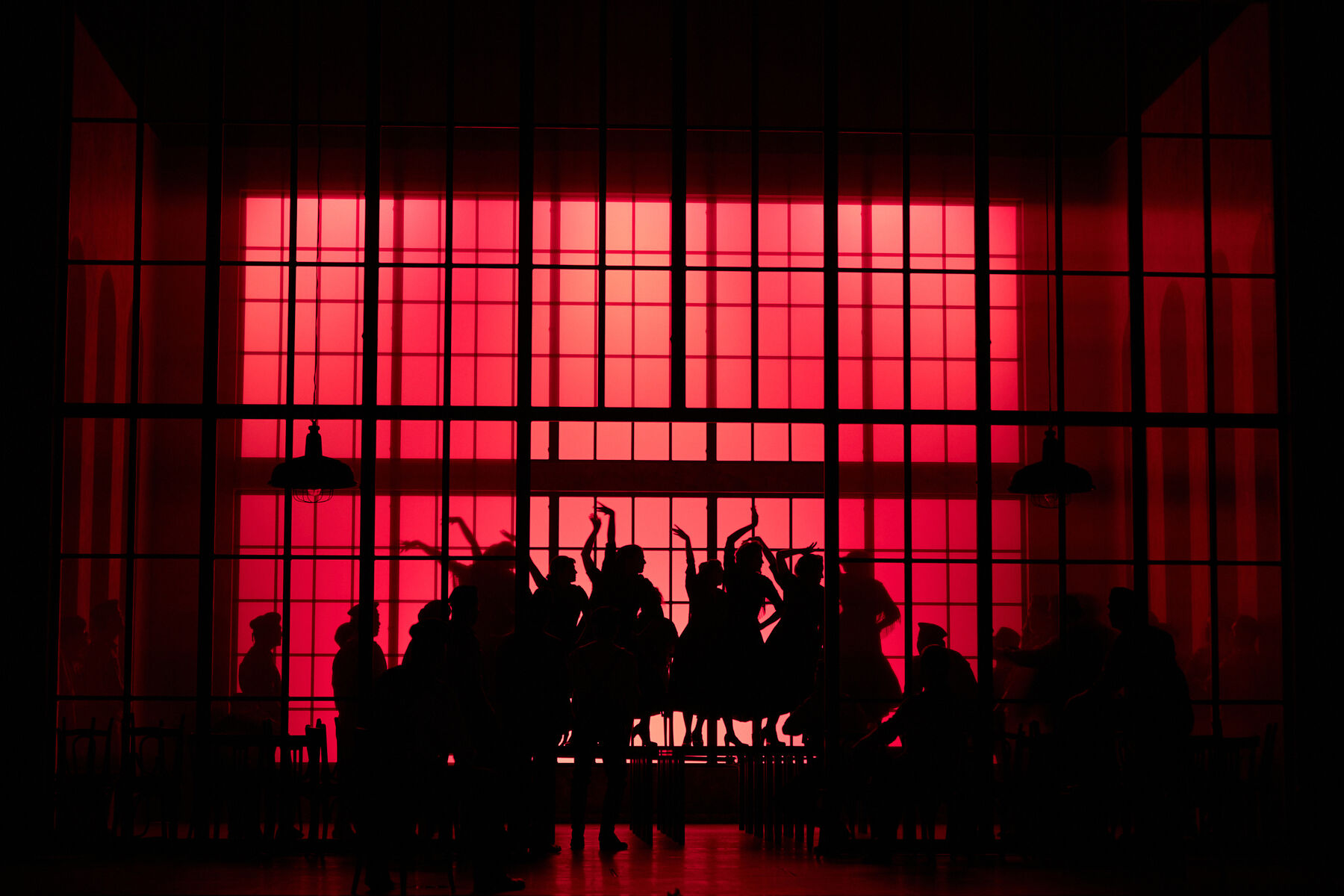 The silhouettes of a group of women can be seen against a red light in the background.