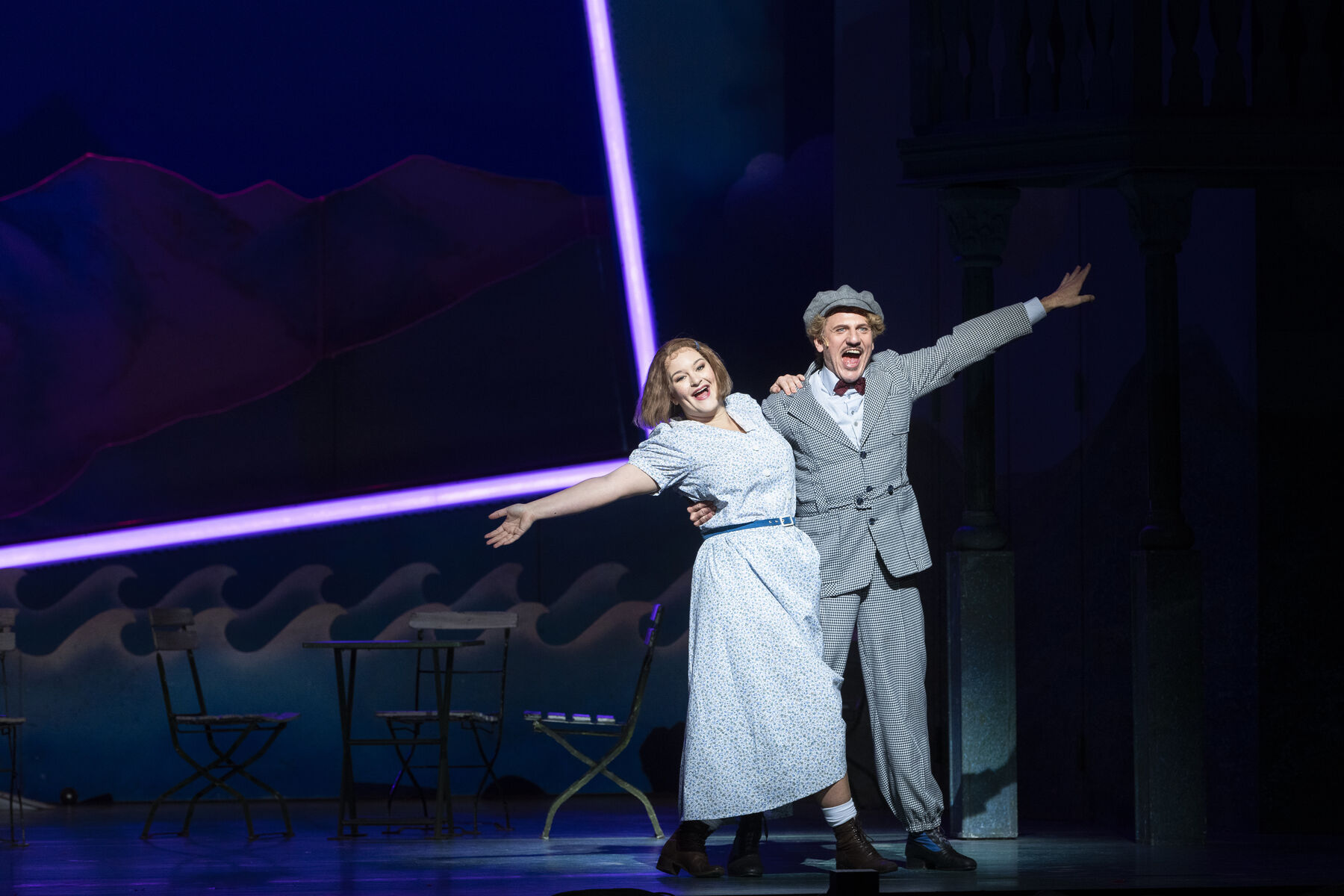 Ein Mann und eine Frau stehen Arm in Arm auf der Bühne. Sie singen.