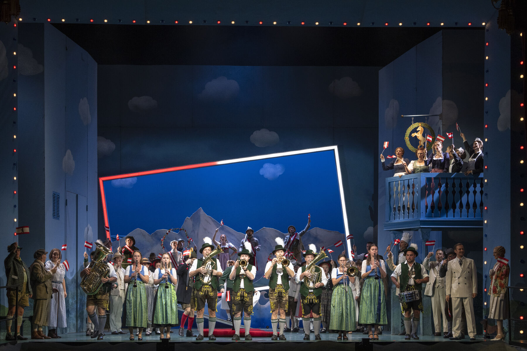 Das Ensemble ist auf der Bühne zu sehen. Manche spielen ein Instrument.