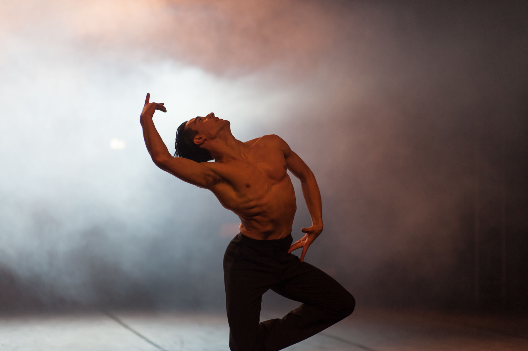 Ein Tänzer steht im Nebel.