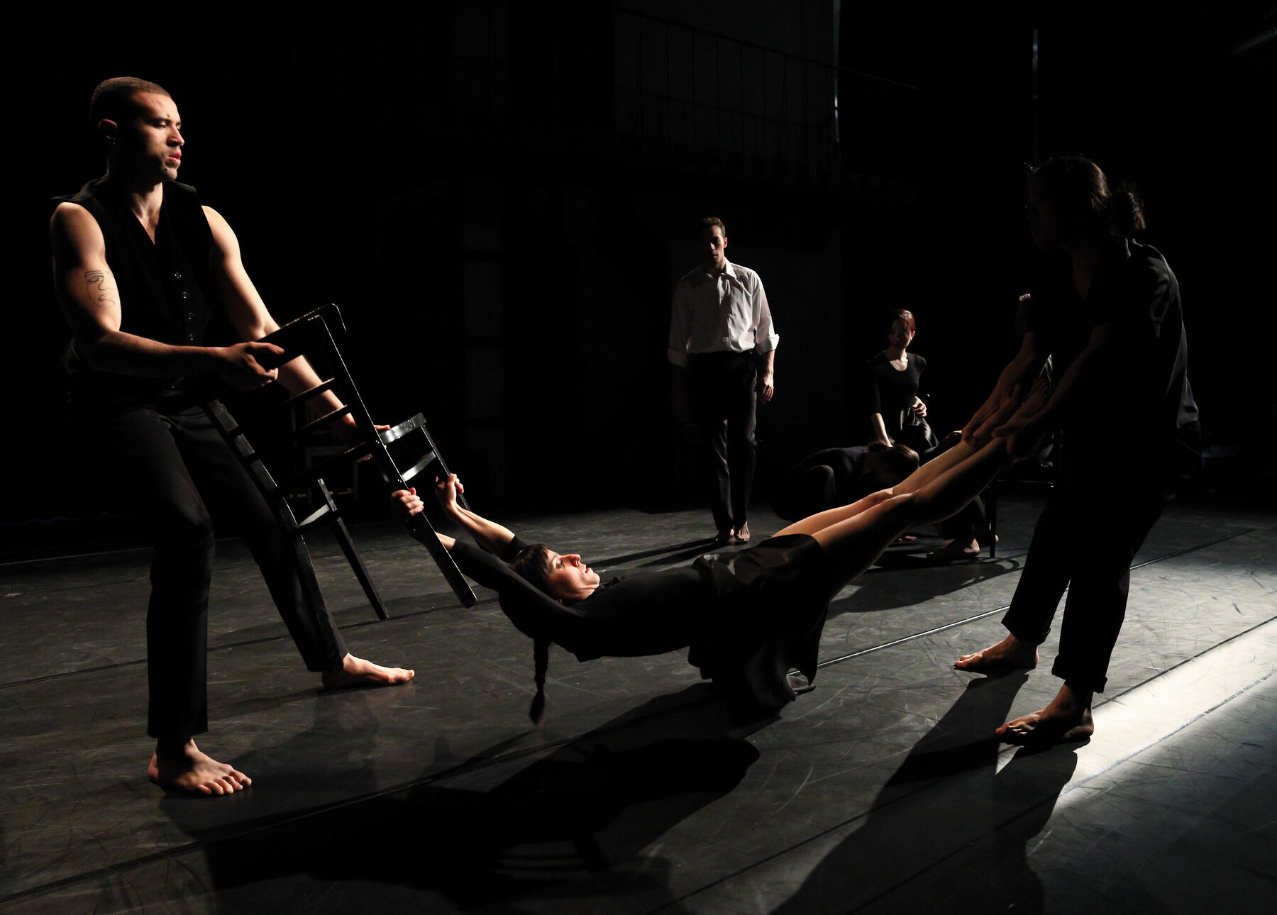 In the foreground three dancers can be seen. They dressed black. In the Background can be seen other dancers.