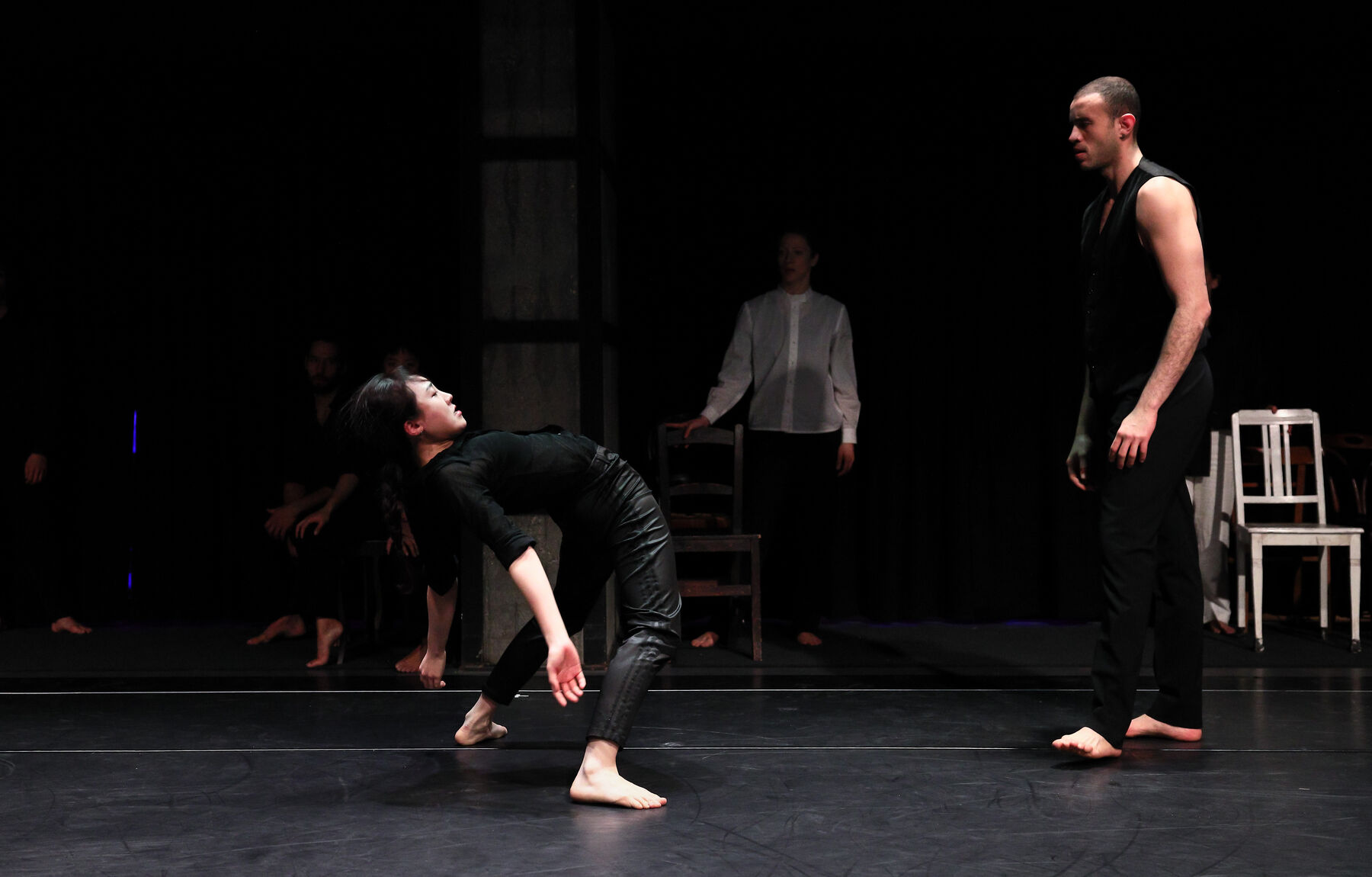 Dancers can be seen in a dark room. In the background can be seen other dancers.