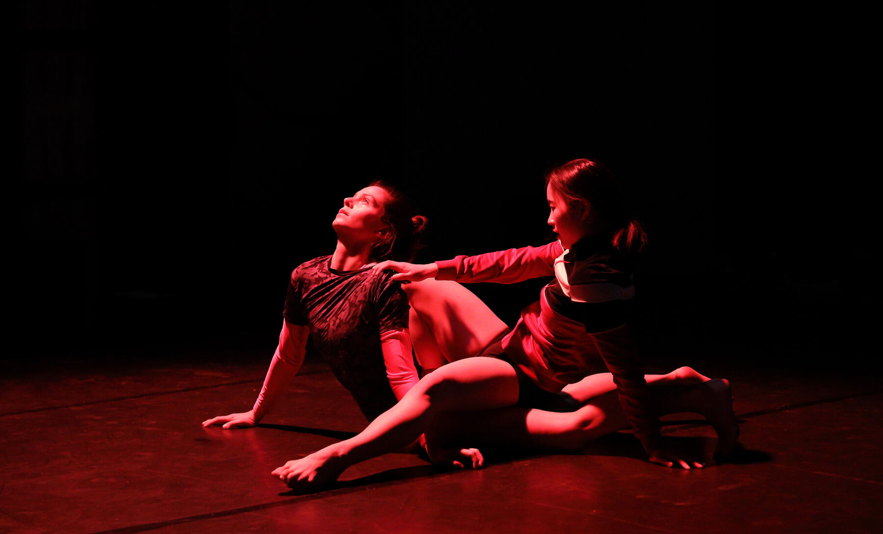 Two dancers can be seen in room, with red lights.