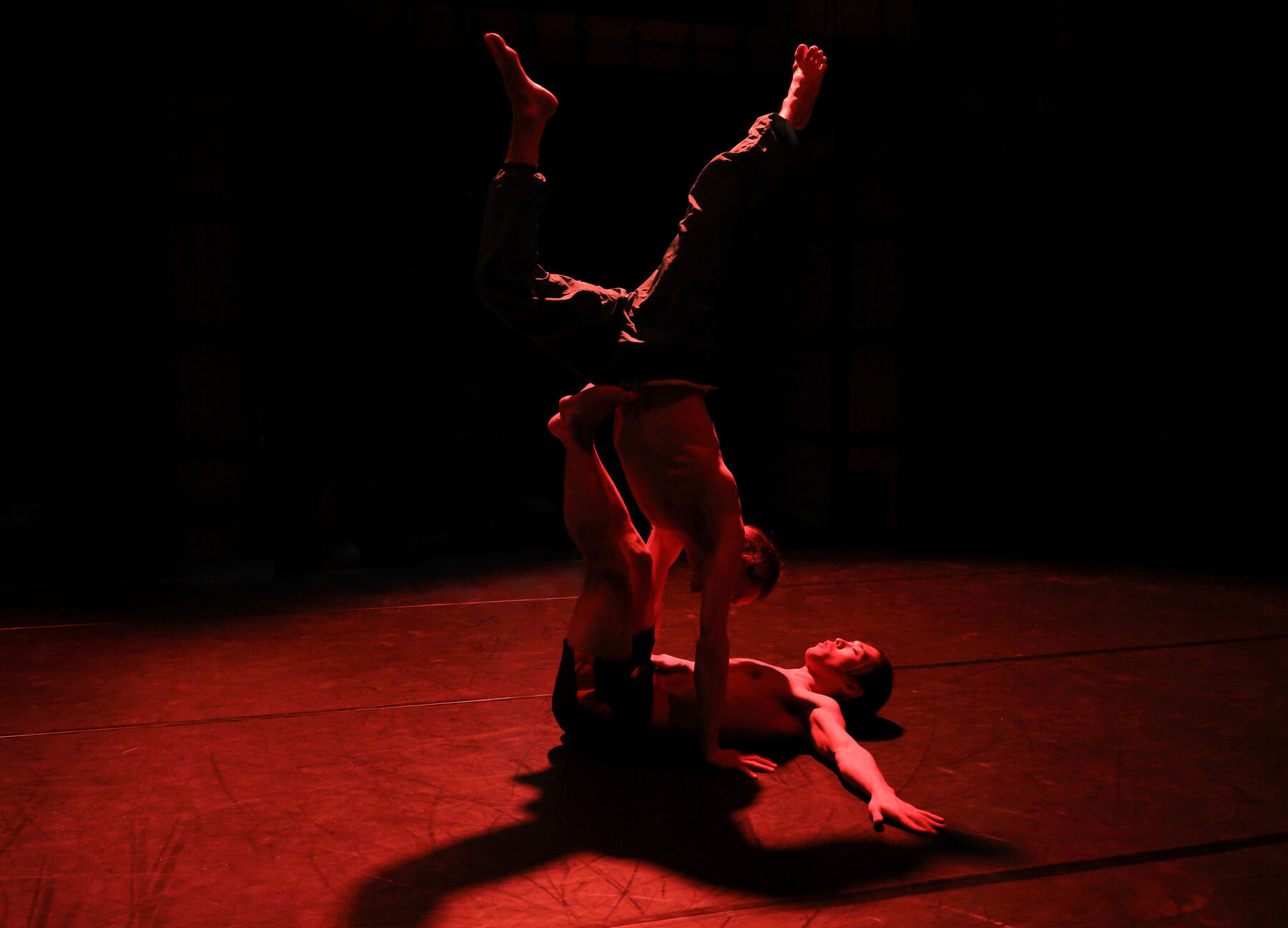 Two dancers can be seen in a dark room with red ligths.