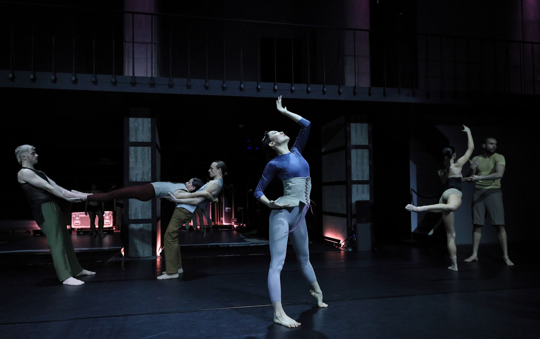 Ballet dancers can be seen in a dark room.