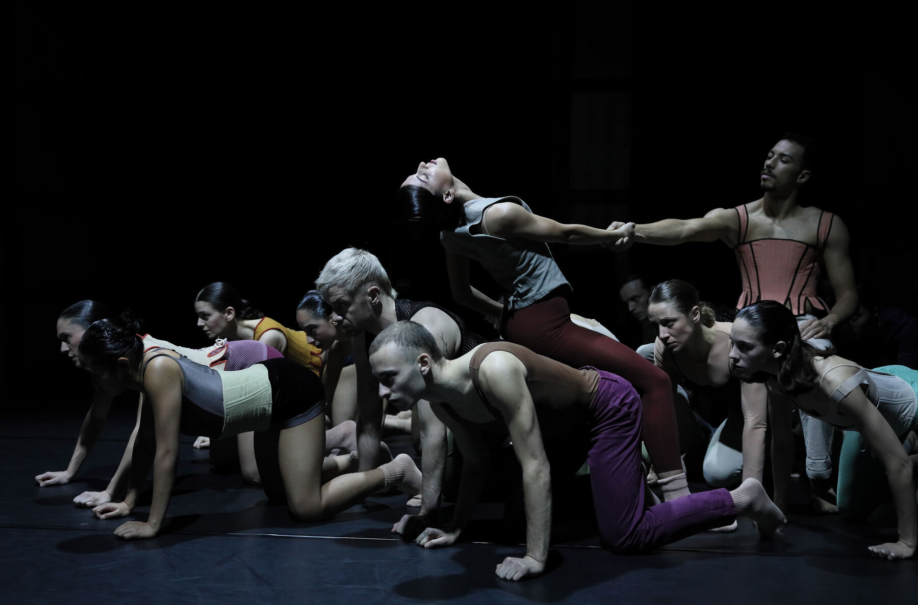 Dancers can be seen in a black Room. Theay are kneeling on the floor.