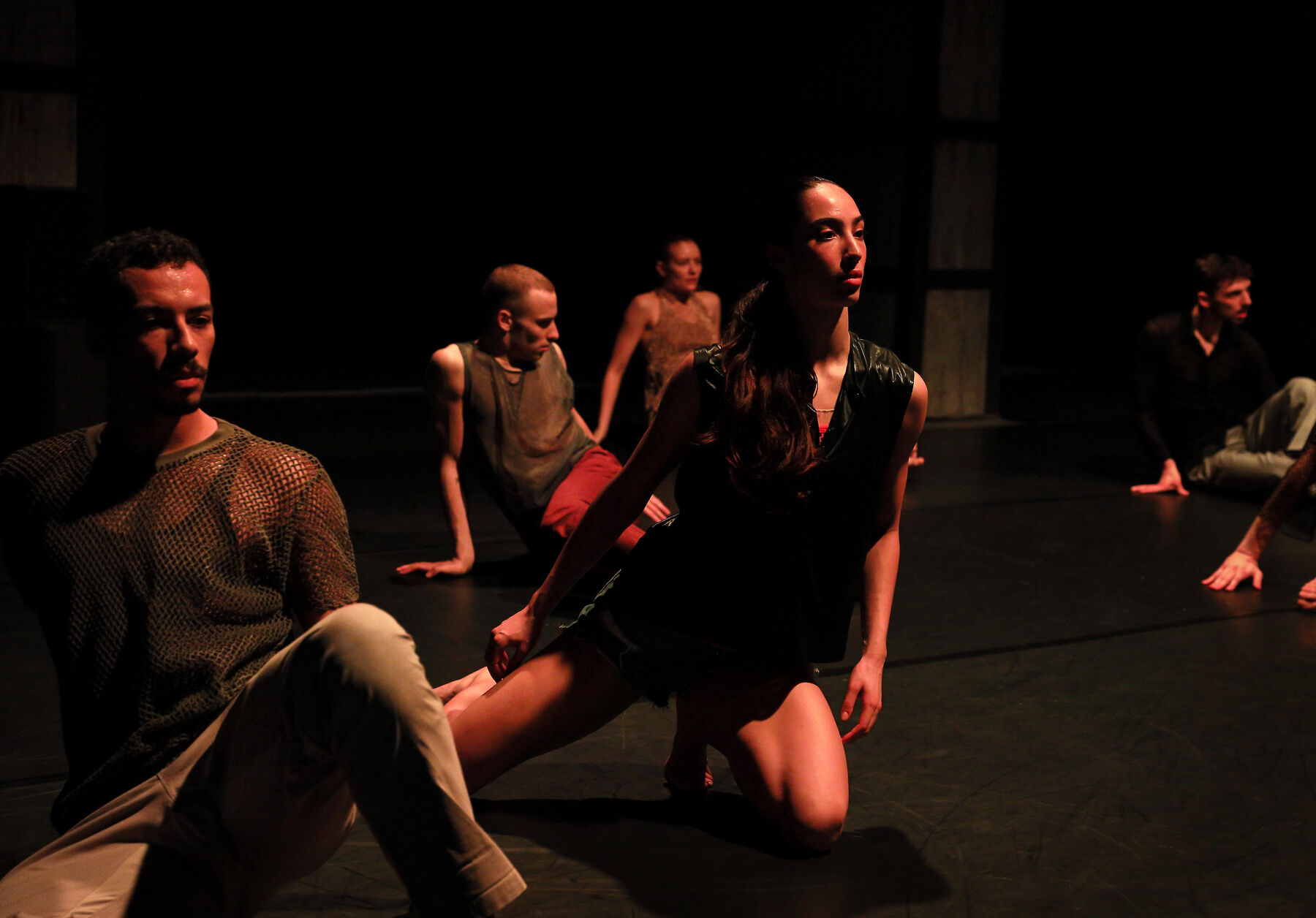 Dancer can be seen in a dark room. Red Light shines onto them.
