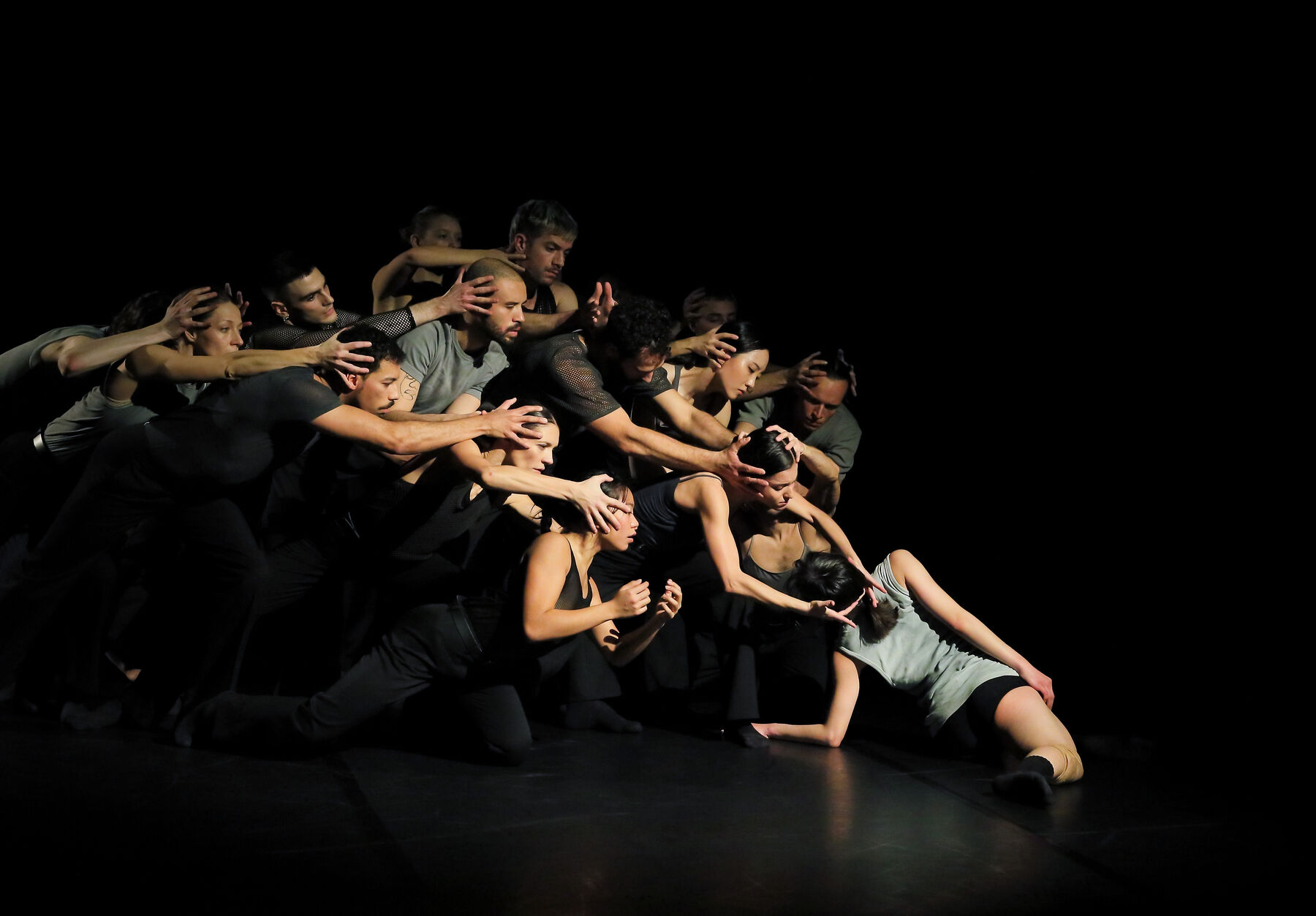 Tänzer sind in schwarz, in einem schwarzen raum zu sehen.