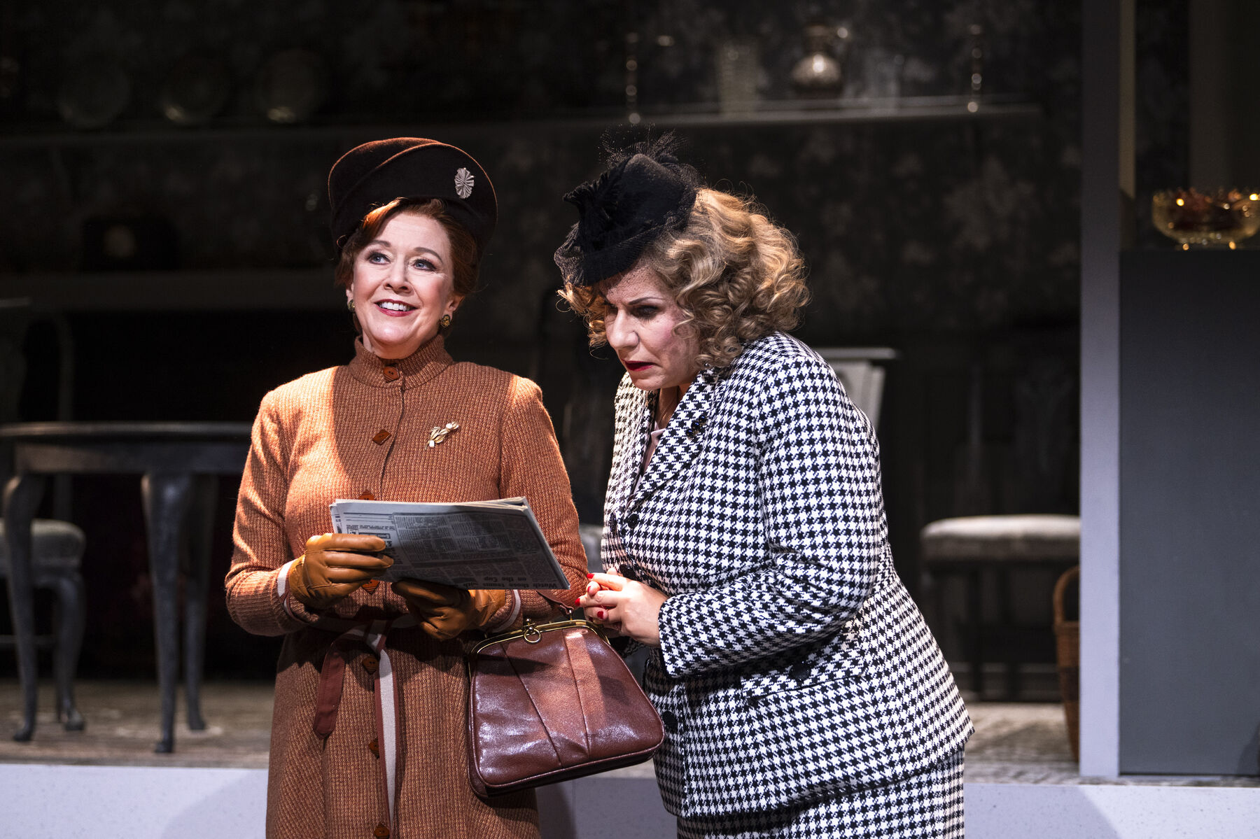 Miss Pinkerton zeigt Miss Todd lachend einen Zeitungsartikel. Miss Todd ist besorgt. 