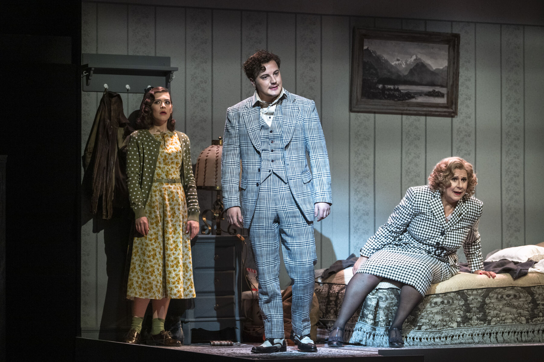 Miss Todd is sitting on a bed, she is distraught. Bob and Laetitia are standing next to the bed. Bob is angry, Laetitia is slightly shocked.