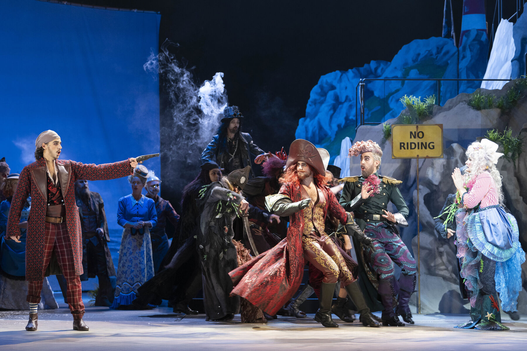 Young Frederic threatens his former nanny Ruth with a pistol. She begs for mercy with her hands clasped together. Behind them stand the other pirates, who are very frightened by this situation.