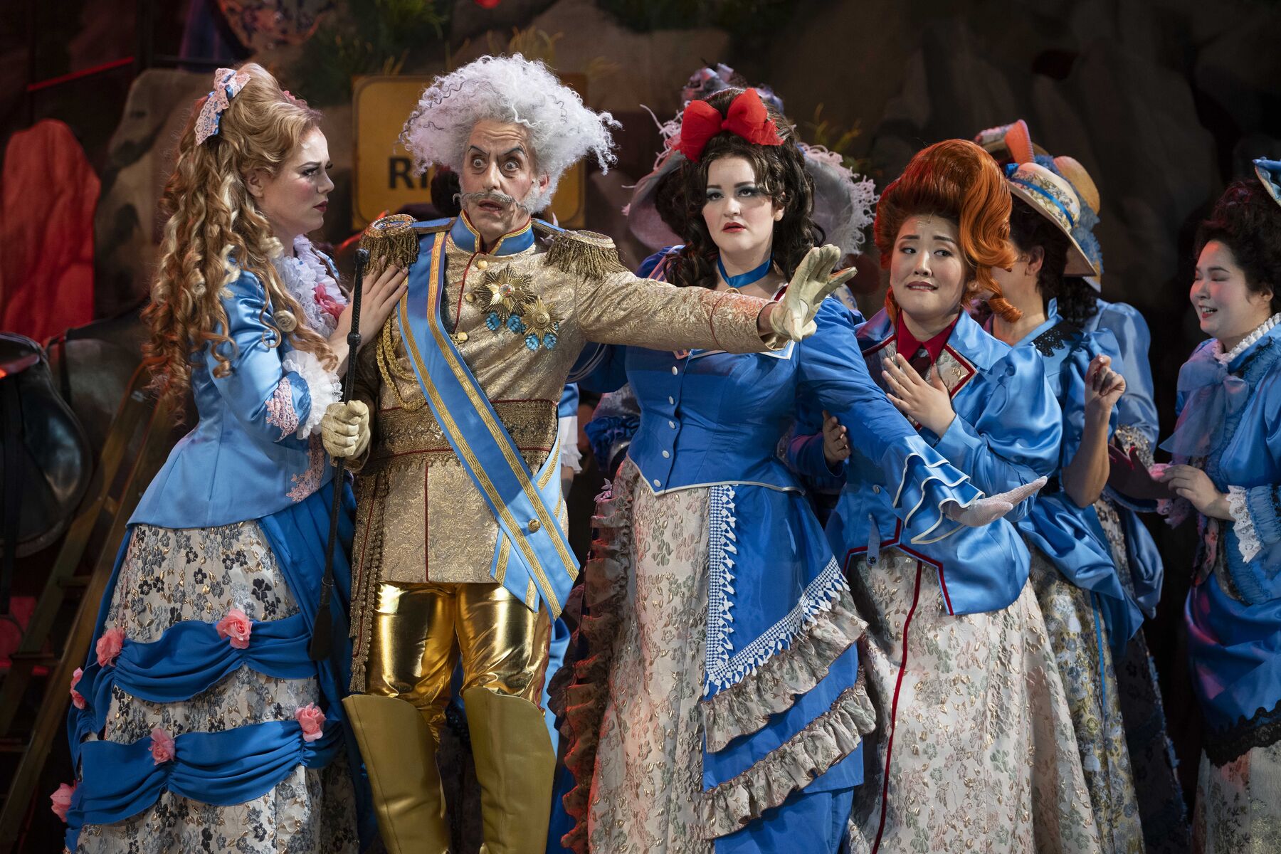 Major General Stanley looks shocked. His wards Isabel, Kate and Edith are with him. Isabel looks at him with concern and puts a hand on his shoulder. He holds the other two behind him with his arm outstretched.