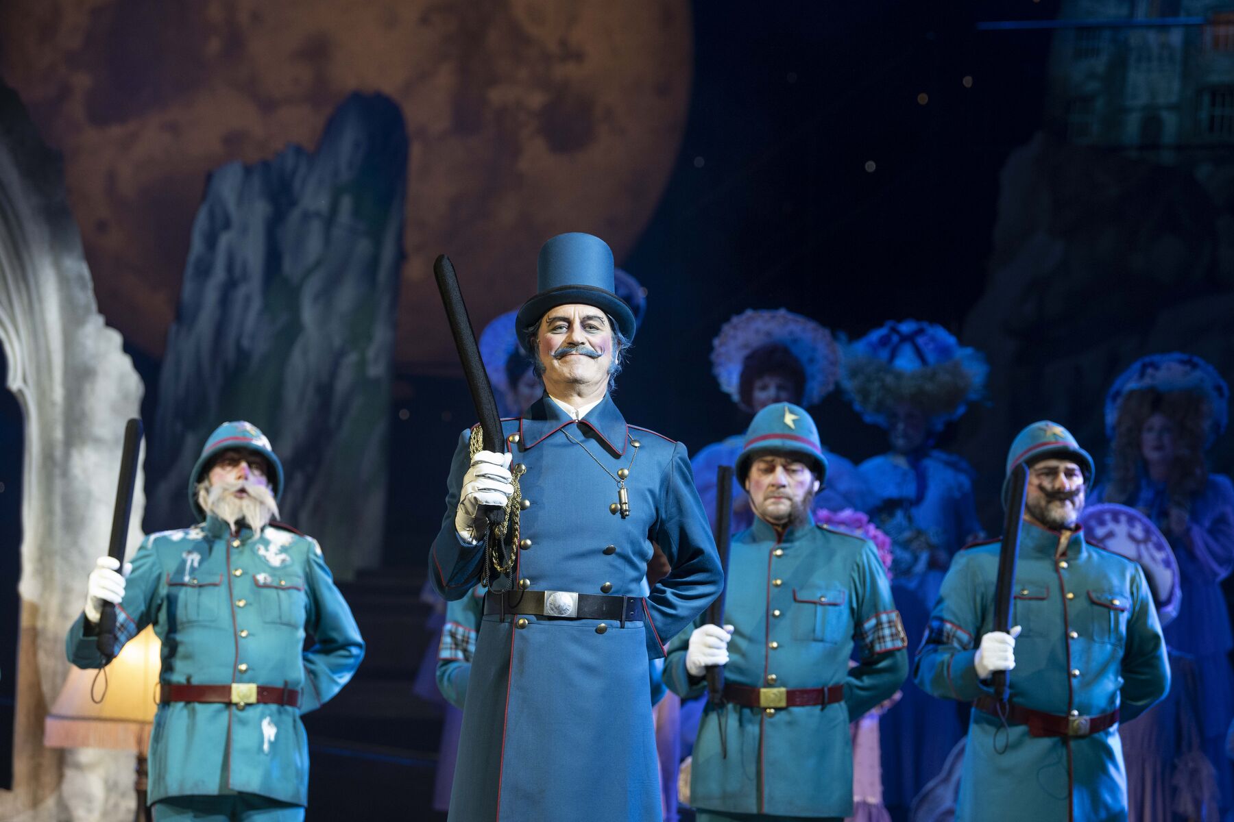 The police officers stand upright with their batons raised behind the police sergeant, who is also standing in this position. The sergeant looks satisfied, while the officers appear rather frightened.