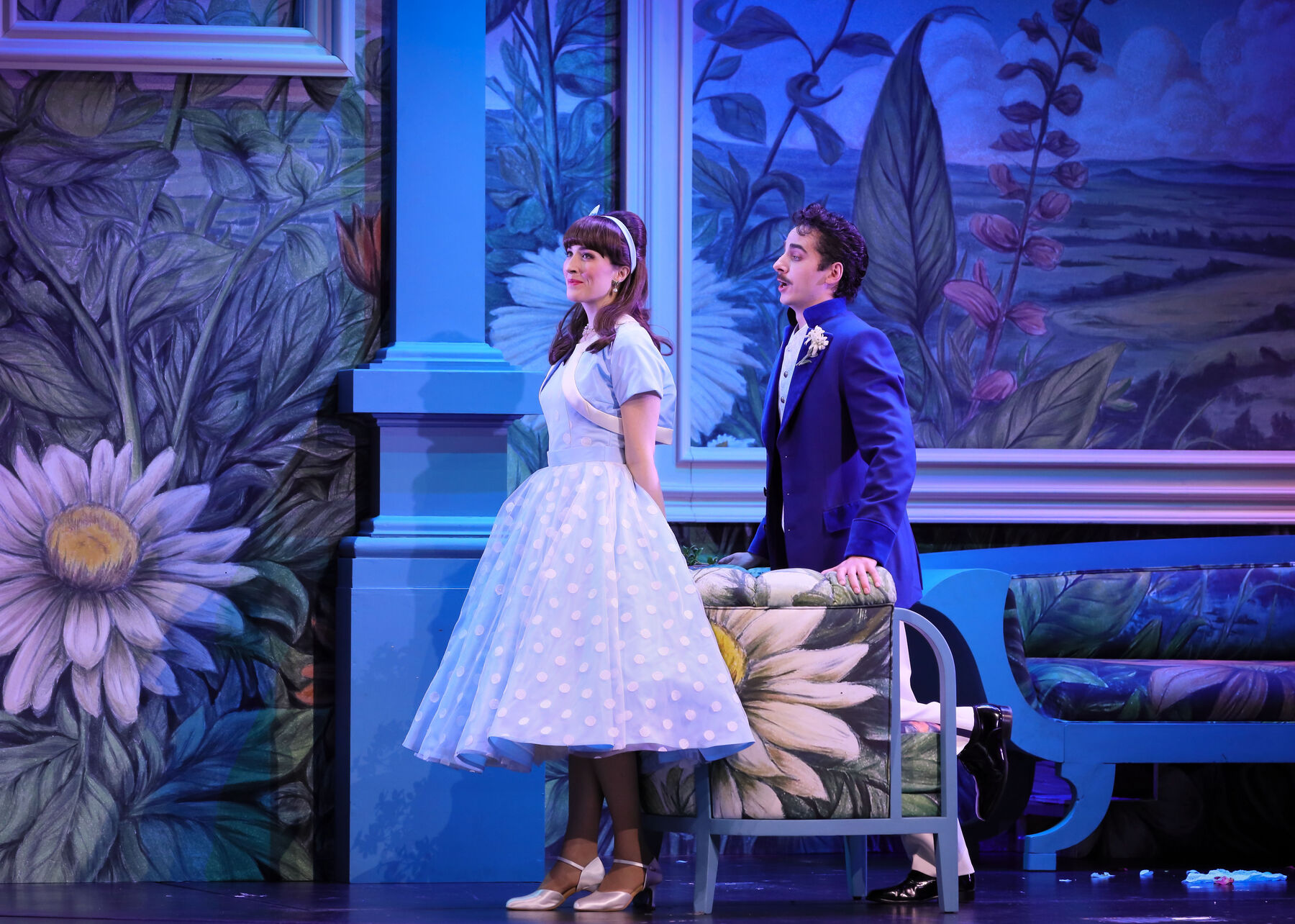 Freda gazes amusedly into the distance while Botho kneels behind her on a chair and charms her. The lighting in this scene is rather dark and cool. It takes place at the Heffeles' estate.