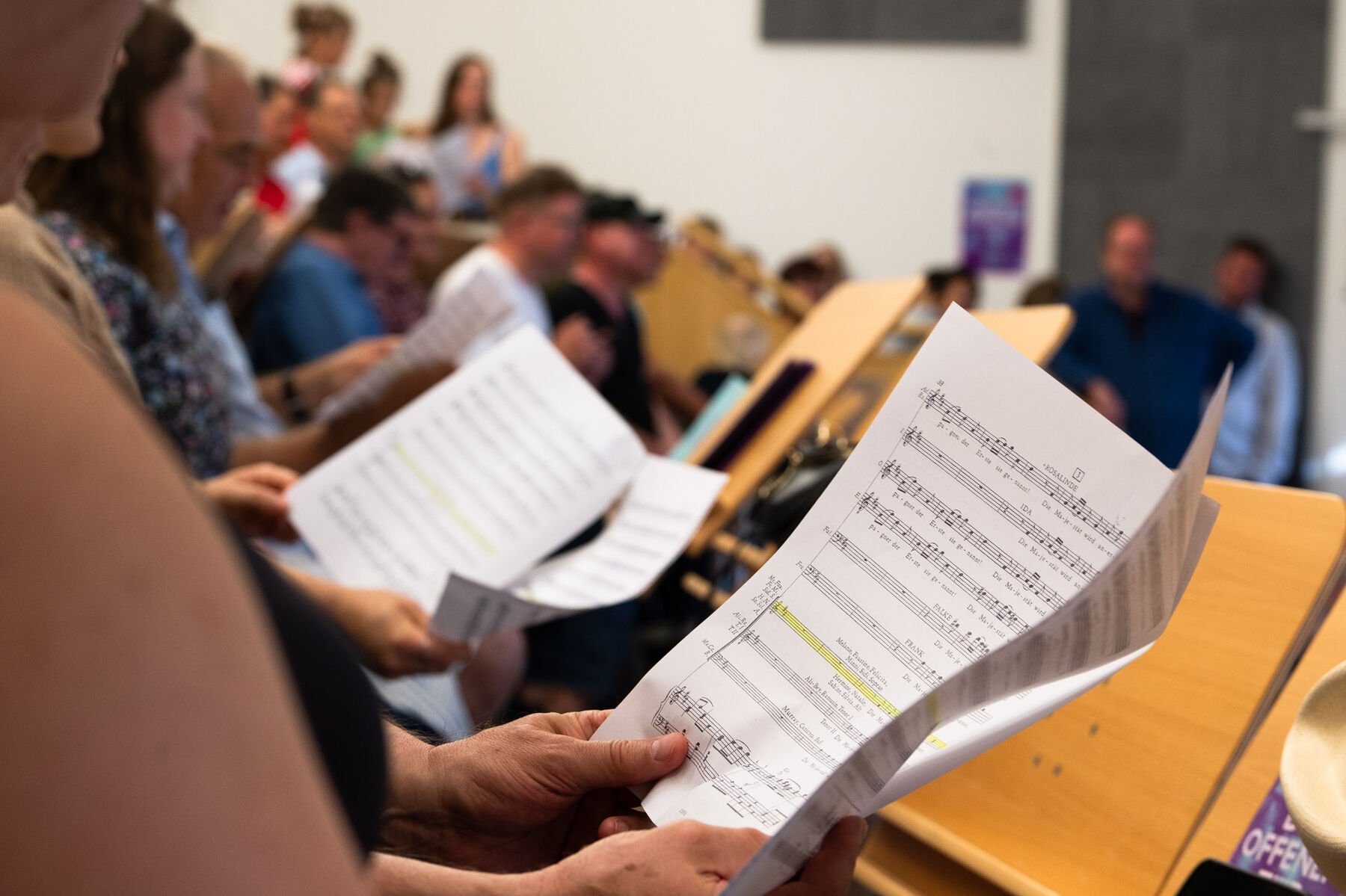 Die Besucherinnen und Besucher halten Notenblätter und singen