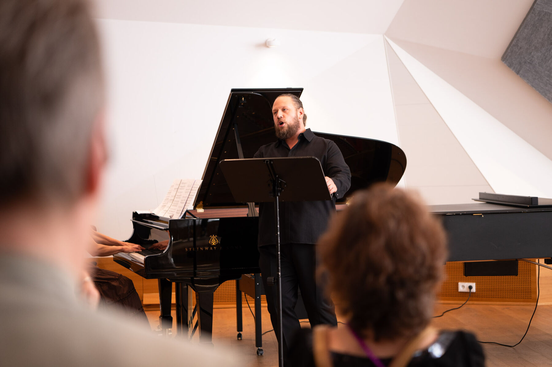Matija Meić steht vor einem Flügel und singt für die Besucherinnen und Besucher